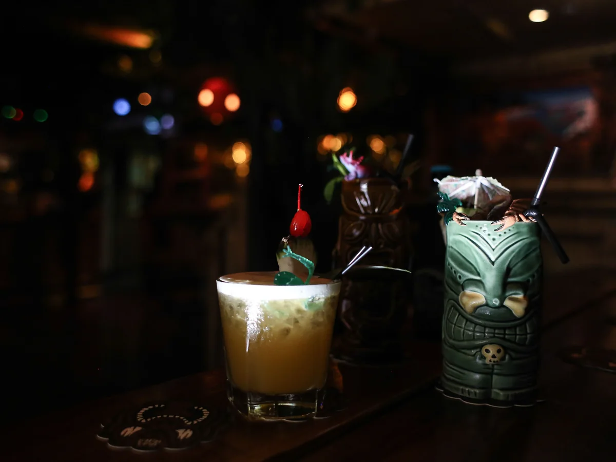 Koktajl w stylu Mai Tai i kubki tiki na ciemnym blacie barowym